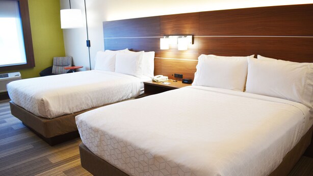 A hotel room with two beds, a nightstand, a chair, and a lamp. - Holiday Inn Express & Suites Albany by IHG (Albany)