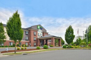 Een Holiday Inn Express & Suites hotel met een bakstenen gevel, een overdekte entree en een aangelegde voortuin.