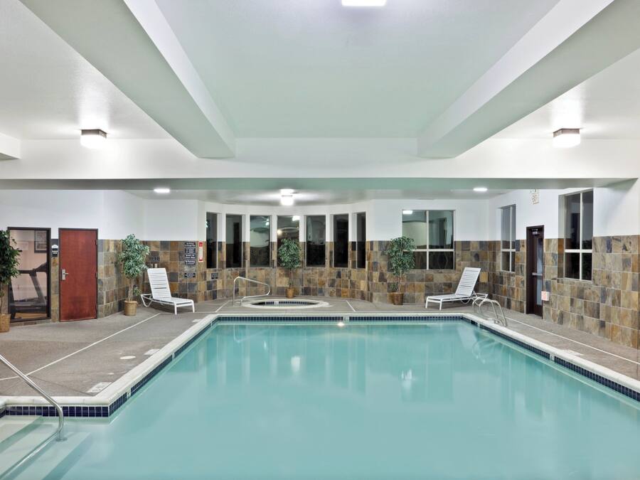 An indoor swimming pool with clear water, surrounded by lounge chairs and potted plants.