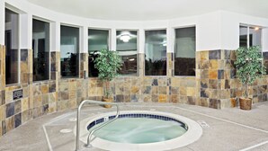 A spa area with a hot tub, stone walls, and large windows. - Holiday Inn Express & Suites Albany by IHG (Albany)