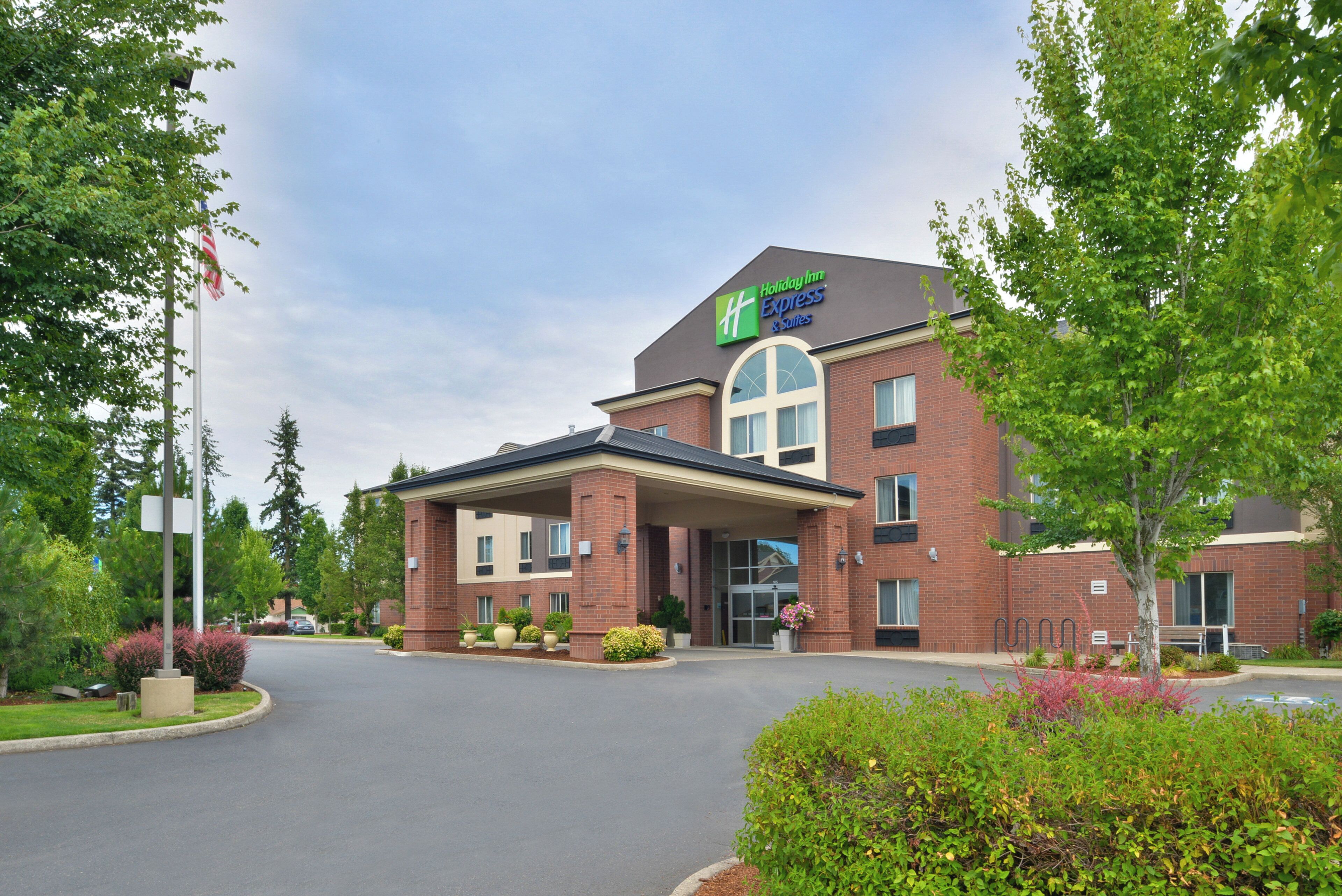 A Holiday Inn Express & Suites with a brick facade, large windows, and a covered entrance.