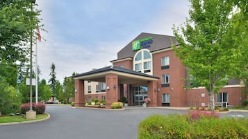 A Holiday Inn Express & Suites with a brick facade, large windows, and a covered entrance.