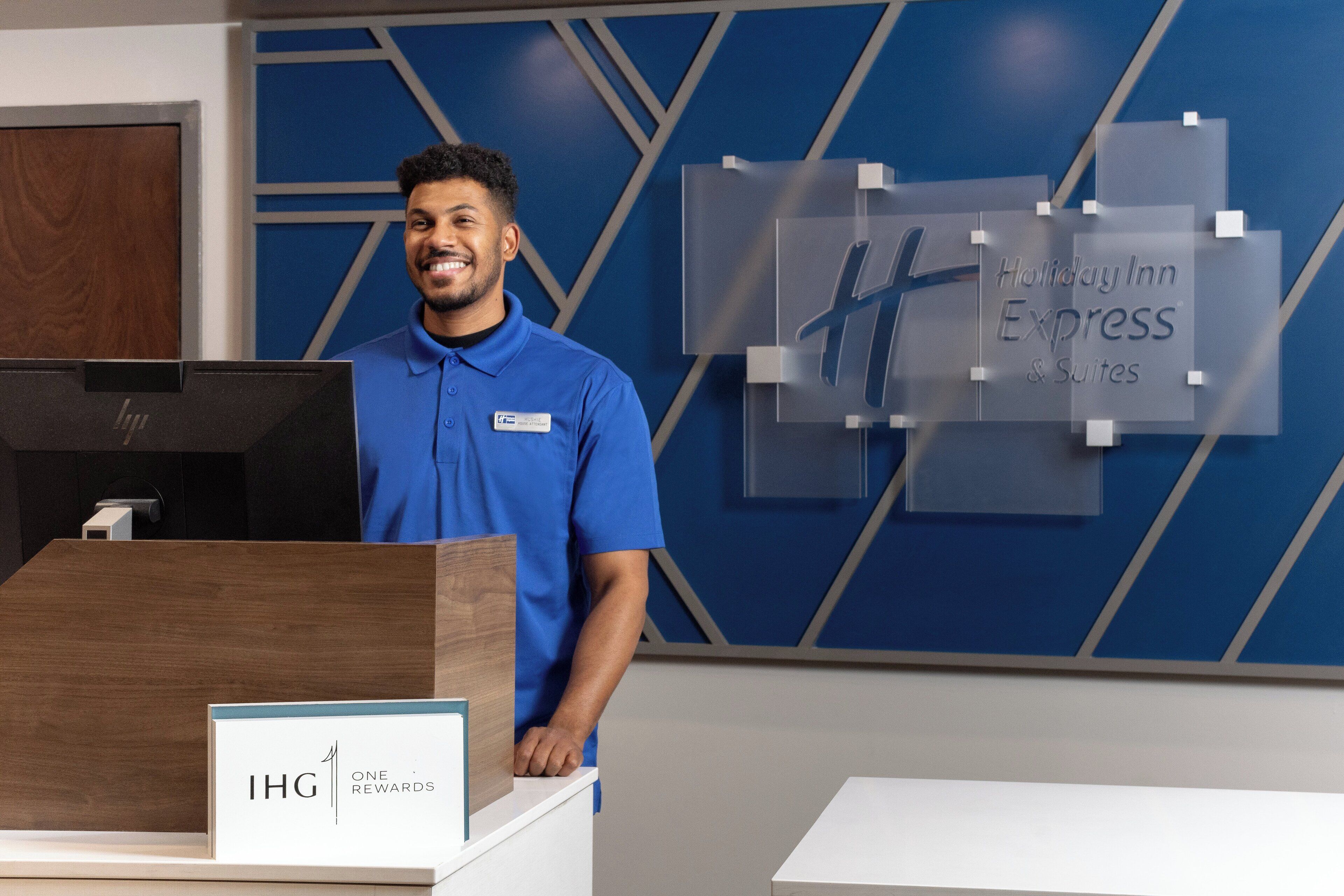 Ein Empfangsschalter des Holiday Inn Express & Suites mit modernem Design, einer Holztischplatte und Namensschildhaltern.