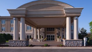 A large building with a covered entrance, columns, and a stone facade. - Holiday Inn Express Hotel & Suites Saginaw by IHG (Saginaw)