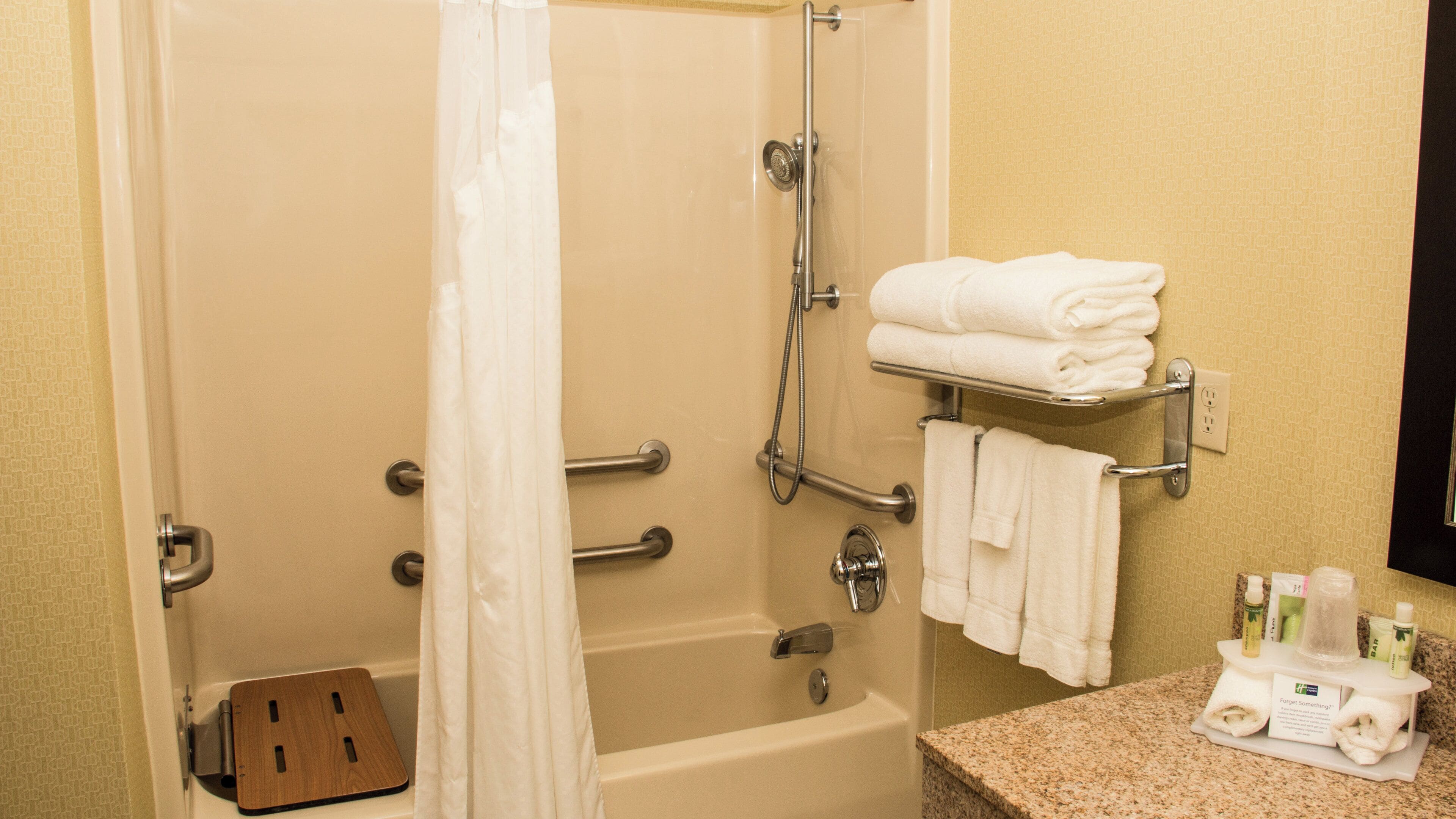 A bathroom with a bathtub, shower, and a towel rack with folded towels.
