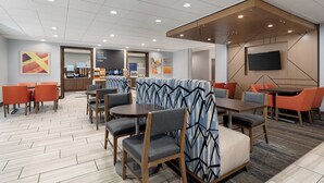 A modern hotel lobby with seating areas, a coffee bar, and a flat-screen TV on the wall. - Holiday Inn Express Hotel & Suites Saginaw by IHG (Saginaw)
