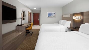 A hotel room with two beds, a desk with a chair, a television, and a door.