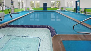 A swimming pool with a blue tiled edge, a hot tub, and a door in the background. - Holiday Inn Express Hotel & Suites Acme-Traverse City by IHG (Williamsburg)