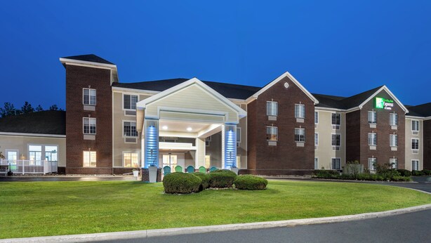 A hotel with a brick facade, a covered entrance, and a well-maintained lawn. - Holiday Inn Express Hotel & Suites Acme-Traverse City by IHG (Williamsburg)