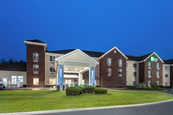A hotel with a brick facade, a covered entrance, and a well-maintained lawn.
