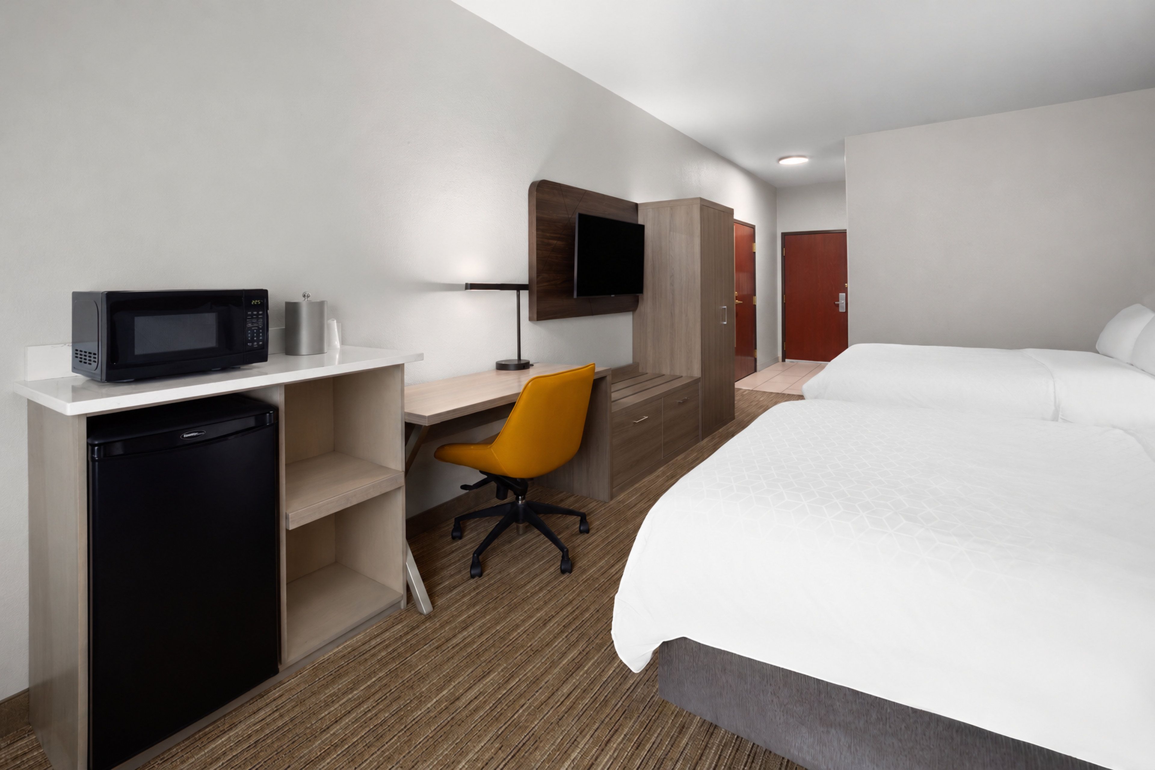 Une chambre d’hôtel comprenant un lit, un bureau avec un micro-ondes, une chaise et un téléviseur.