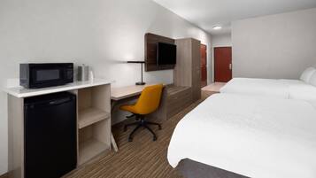 Une chambre d’hôtel comprenant un lit, un bureau avec un micro-ondes, une chaise et un téléviseur.