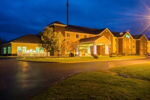 Un hotel con entrada principal, estacionamiento y fachada bien iluminada.