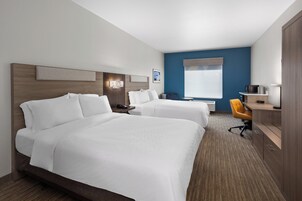Habitación de hotel con dos camas, un escritorio, una silla, una ventana y un televisor instalado en la pared.