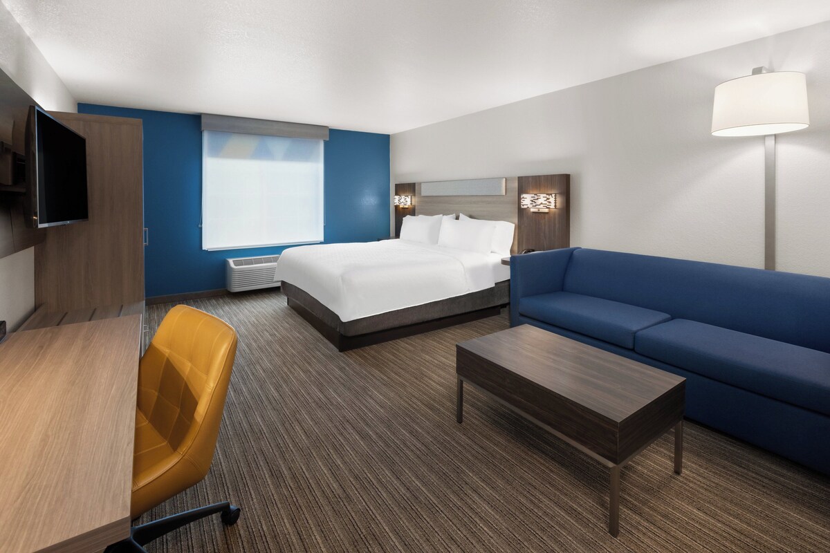 Ein Hotelzimmer mit Bett, einer Couch, einem Schreibtisch, einem Sessel, einem Fernseher und einer Lampe.