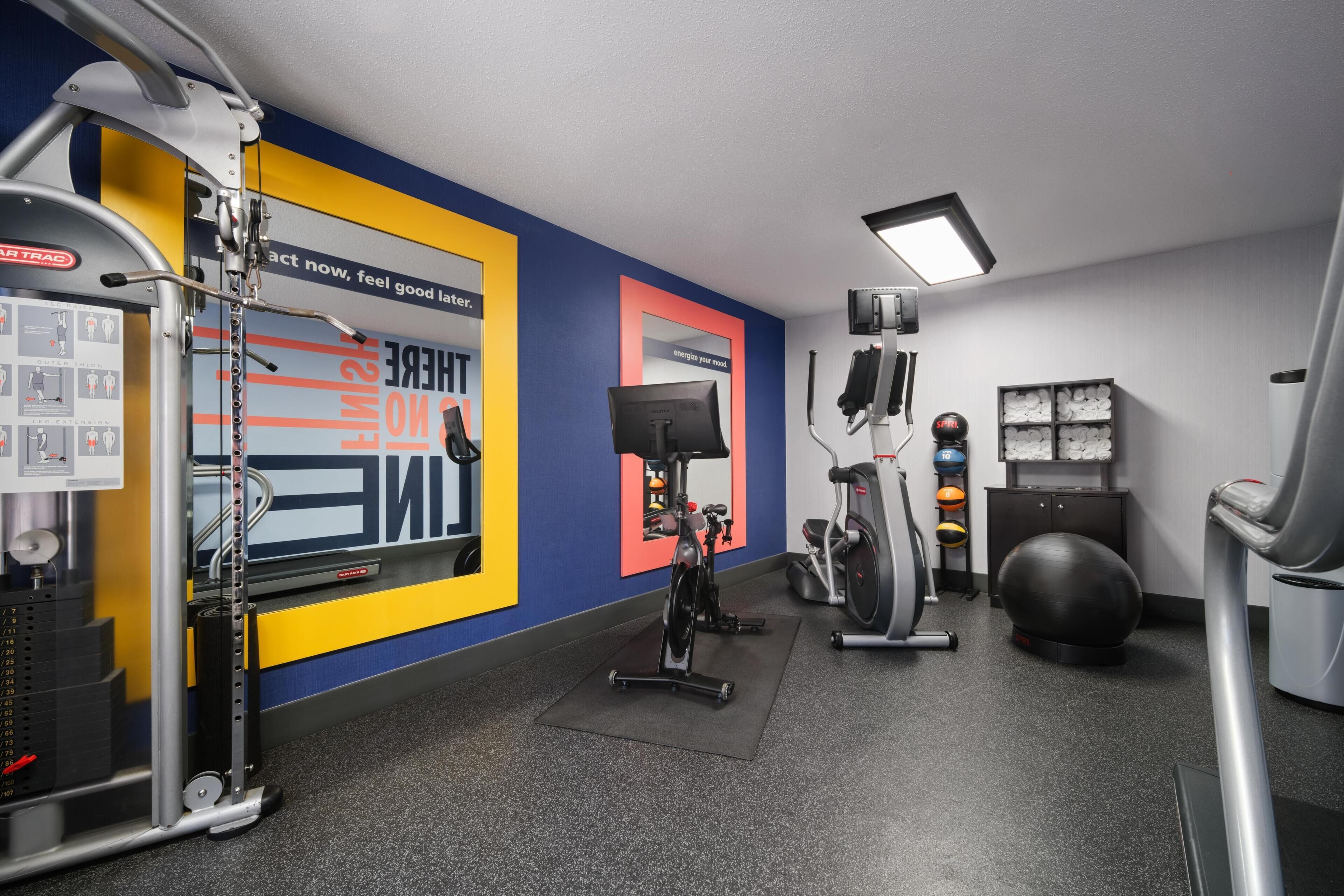 A gym with exercise equipment, a wall with motivational posters, and a mirrored wall.