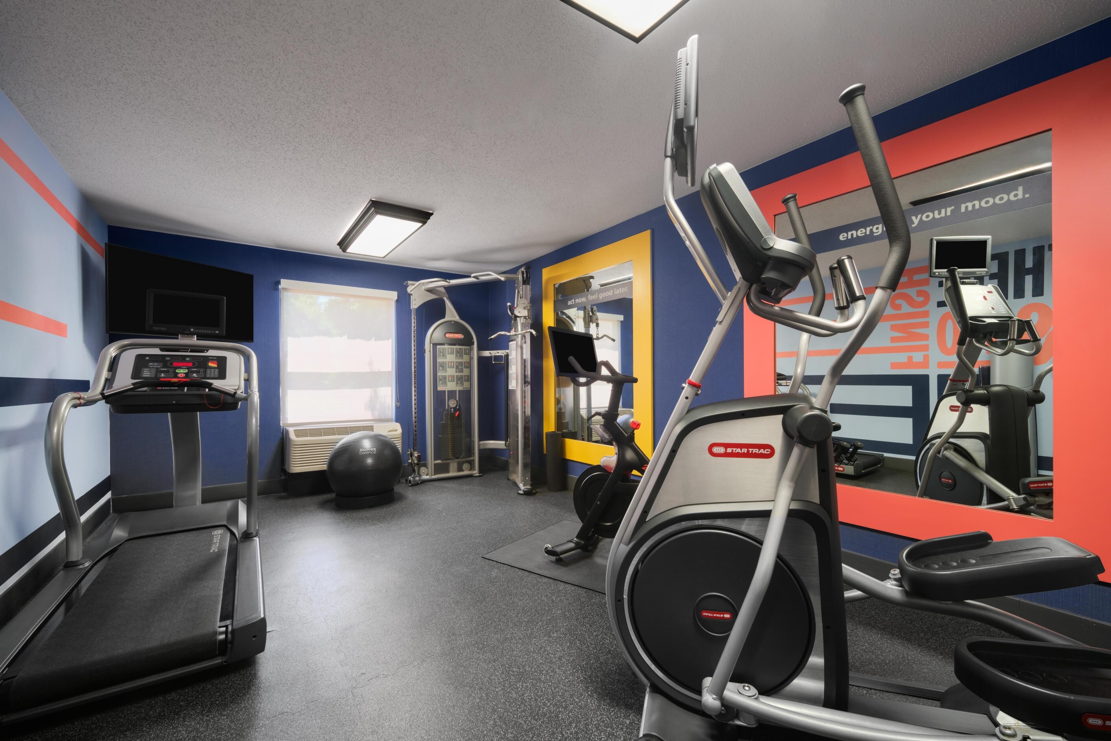 Un gimnasio con cintas de correr, una elíptica y una bicicleta estática.