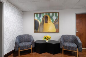 Una habitación con dos sillones estampados, una mesa negra y un cuadro en la pared.