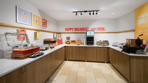 A breakfast area with a counter, food dispensers, and a sign that reads 'HAPPY BREAKFAST STARTS HERE.' - Hampton Inn Havelock (Havelock)