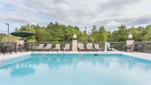 Una piscina rectangular con agua cristalina y azul, rodeada de sillas de descanso y sombrillas.