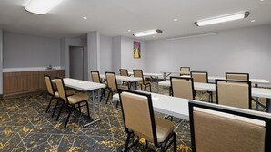 A conference room with tables and chairs, a kitchenette, and a painting on the wall. - Hampton Inn Havelock (Havelock)