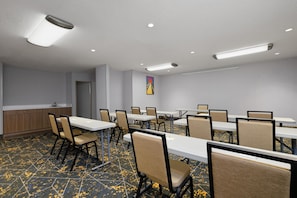 A conference room with tables and chairs, a kitchenette, and a painting on the wall. - Hampton Inn Havelock (Havelock)