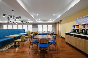 A modern dining area with a blue sofa, wooden tables, and chairs. - Hampton Inn Havelock (Havelock)