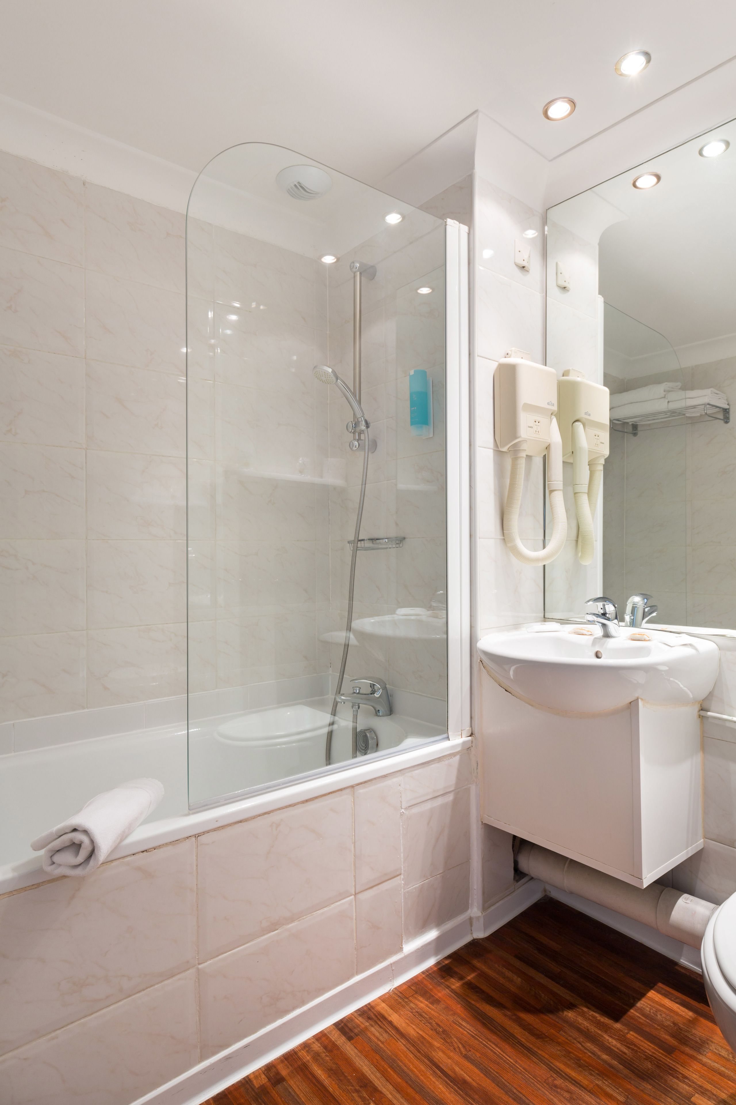 A modern bathroom with a glass-enclosed shower, a white sink, and a mirror.