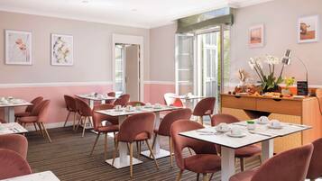 A dining area with tables and chairs, framed artwork on the walls, and a view of the outdoors.