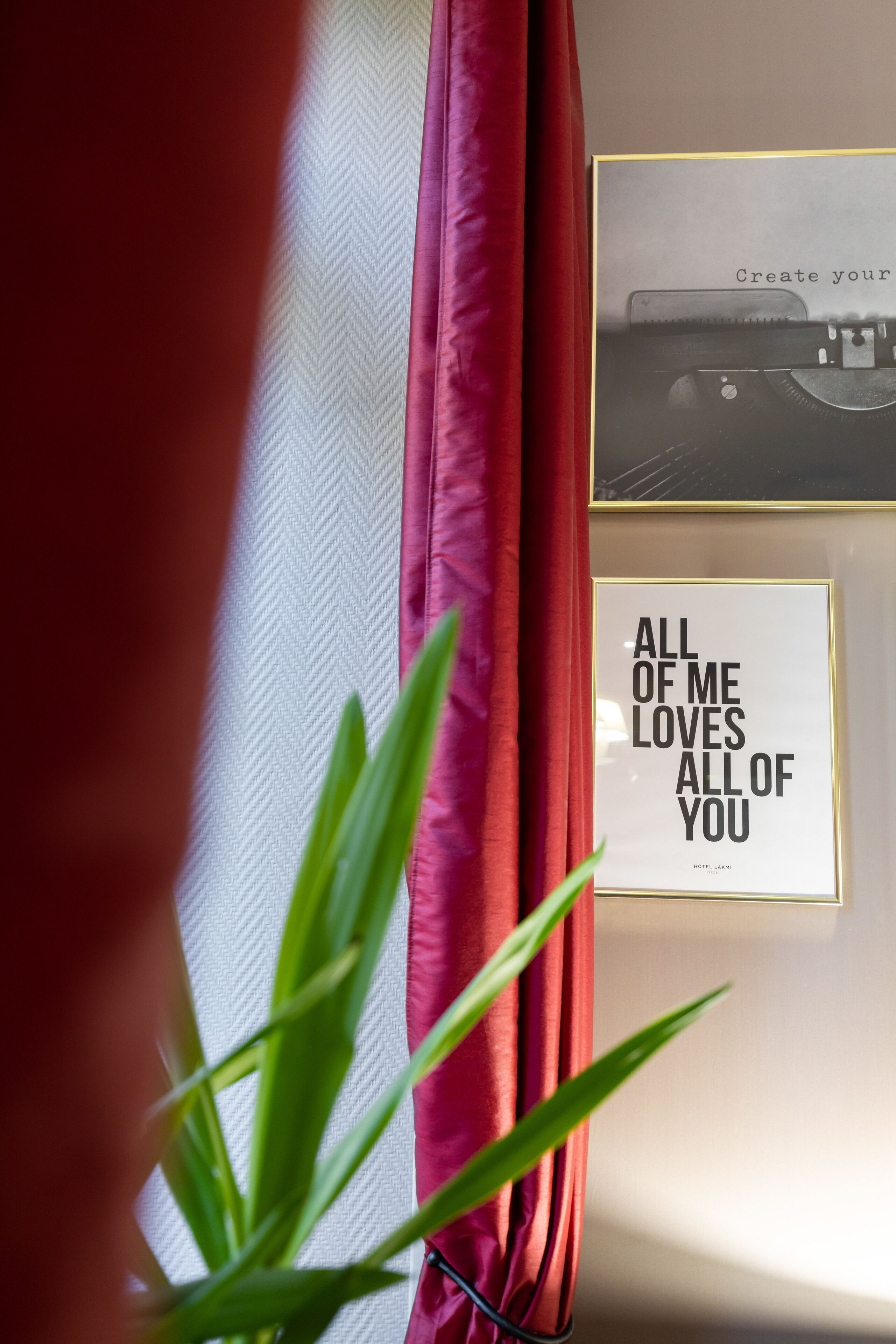 A framed quote on a wall, a typewriter, and a curtain.