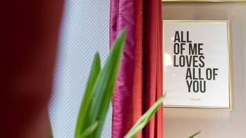 A framed quote on a wall, a typewriter, and a curtain.