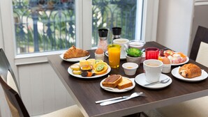 Una mesa de desayuno con platos de comida, un croissant, un vaso de jugo de naranja y una taza de café.