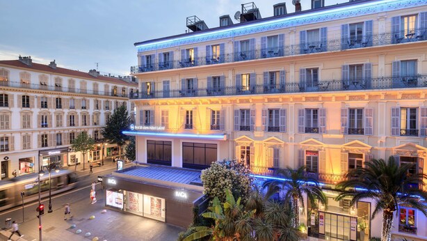 Un hotel con una entrada amplia, varios balcones y una fachada bien iluminada.