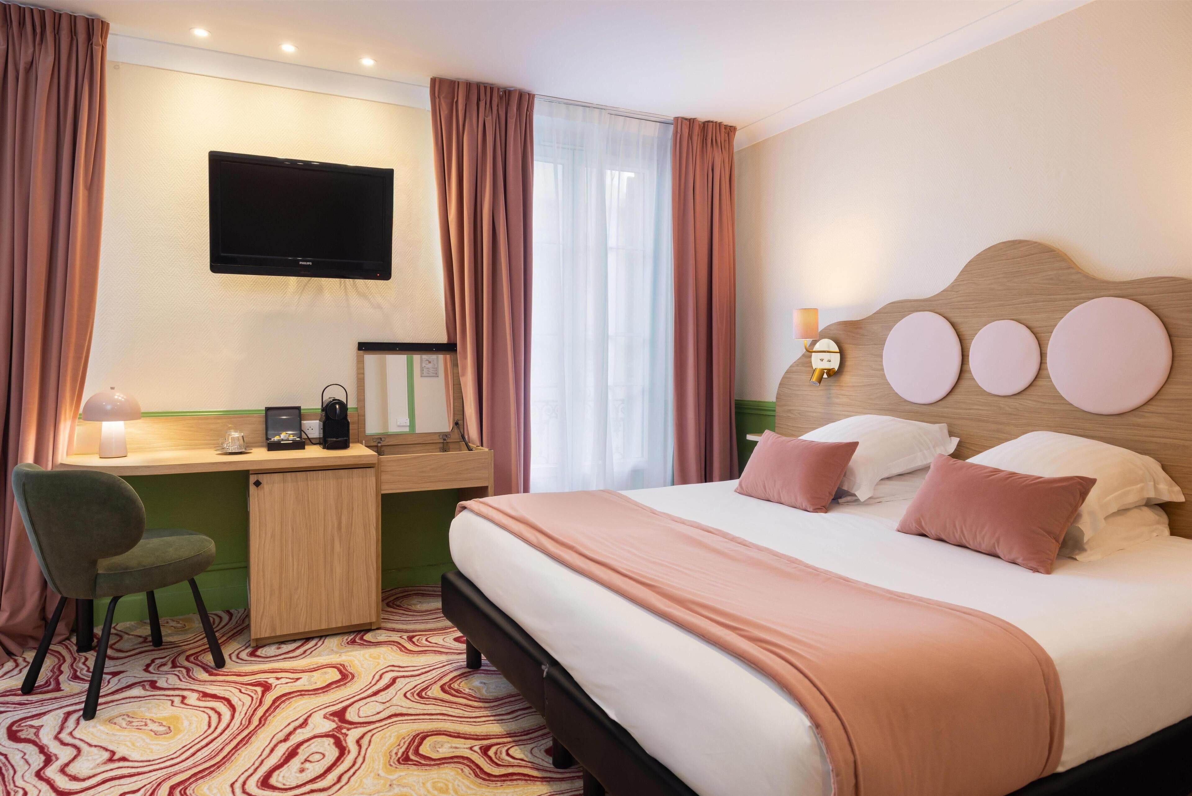 A hotel room with a bed, desk, chair, television, and a window with curtains.