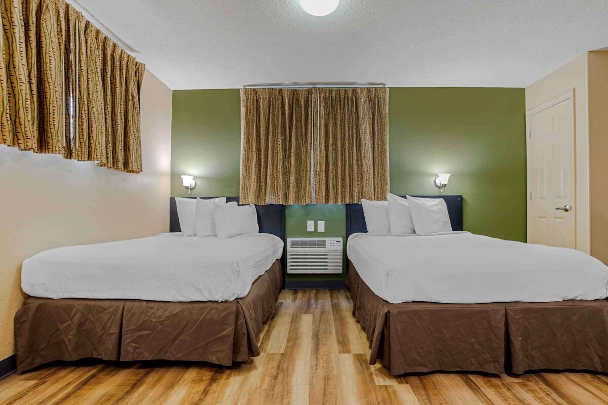 Ein Doppelzimmer mit zwei Betten, Deckenventilator und Klimaanlage.