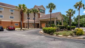 Een Stay America hotel met een overdekte ingang, palmbomen en een parkeerplaats.