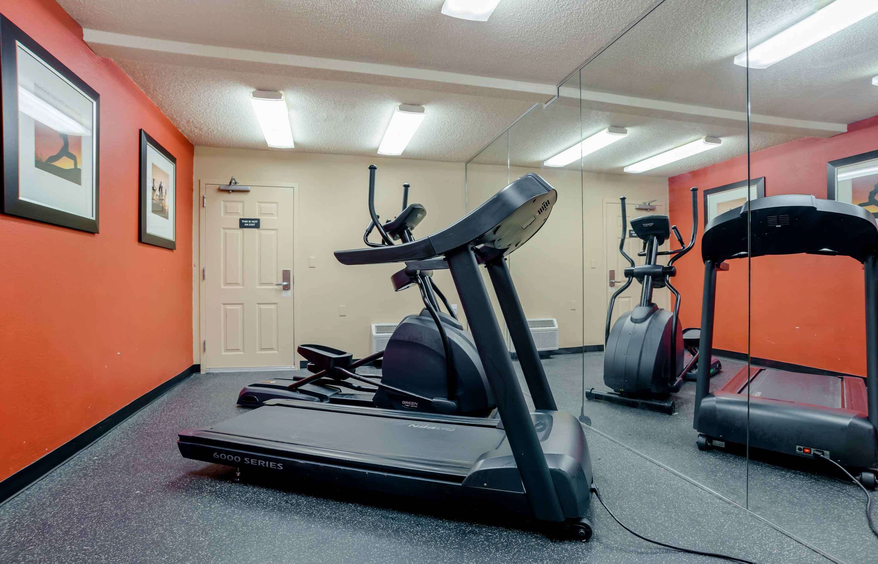 A fitness room with treadmills, an elliptical, and a mirrored wall.