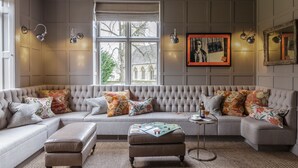 Una sala acogedora con un amplio sofá modular, una mesita auxiliar y un espejo decorativo.
