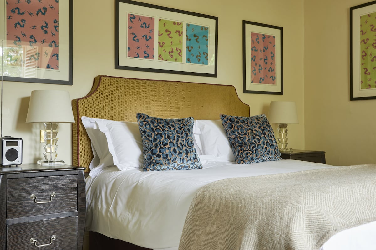A neatly made bed with patterned pillows, a bedside table with a lamp, and framed artwork on the wall.