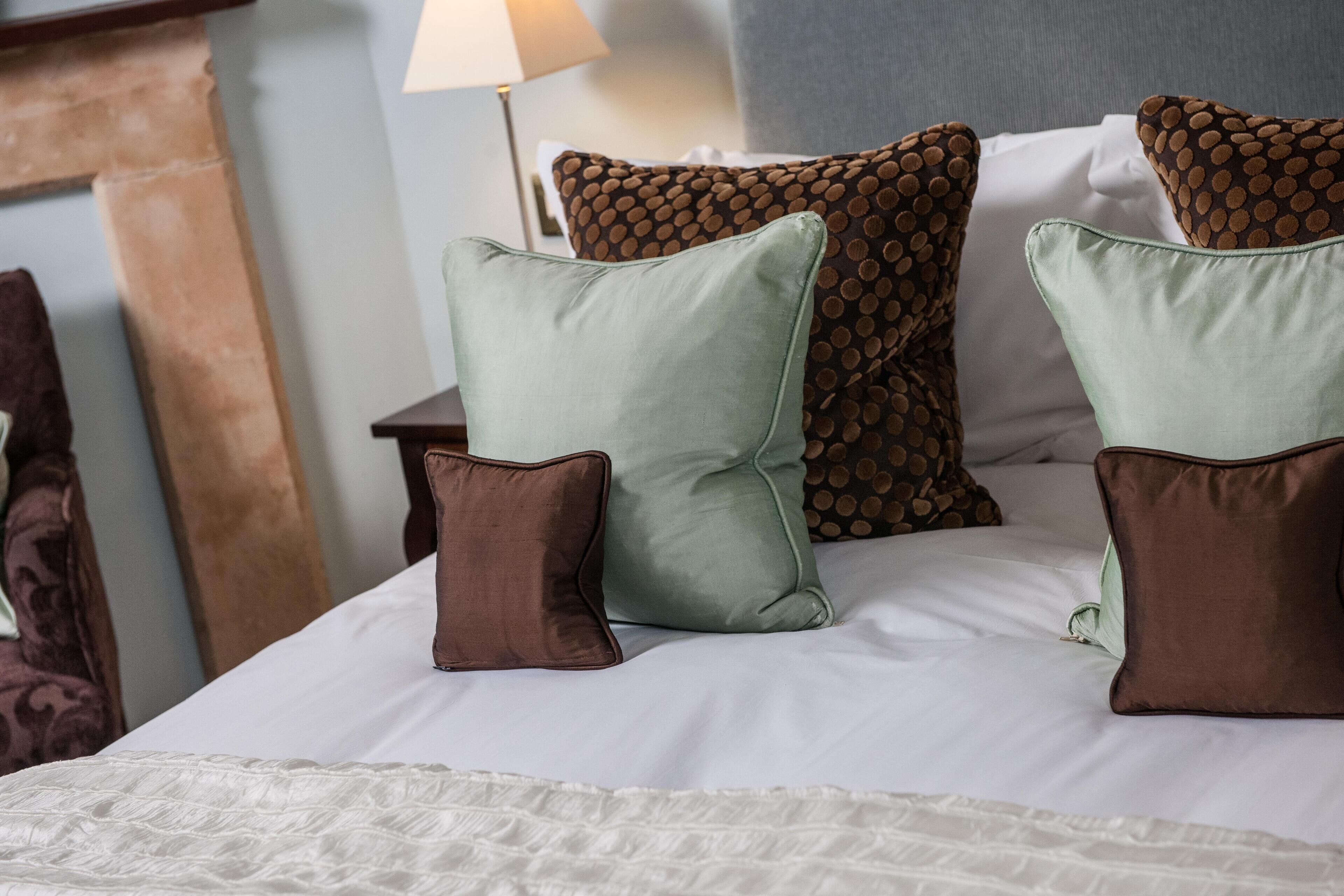 A neatly made bed with multiple pillows and a white bedspread.