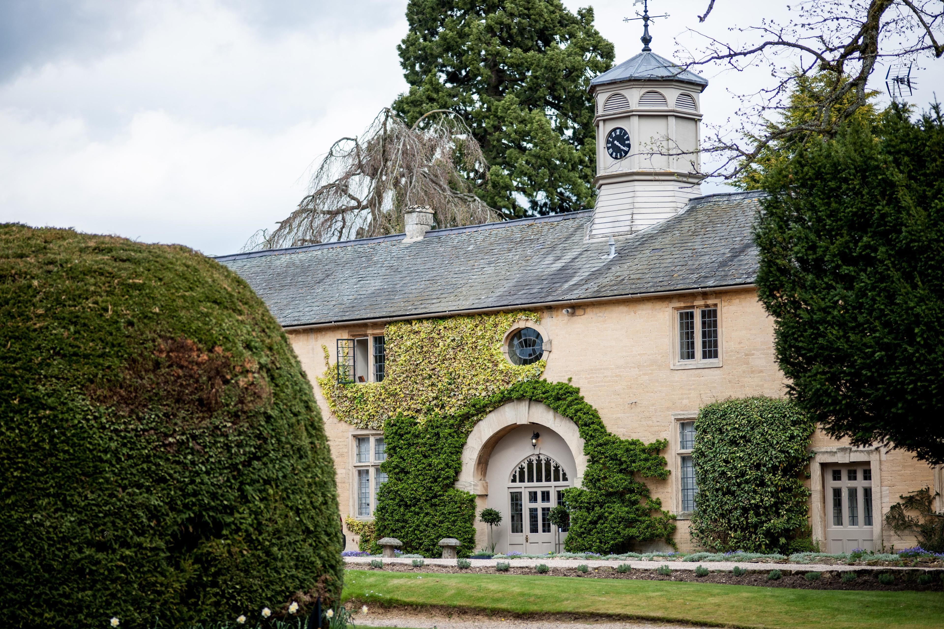 A historic building with a clock tower, arched windows, and ivy-covered walls.