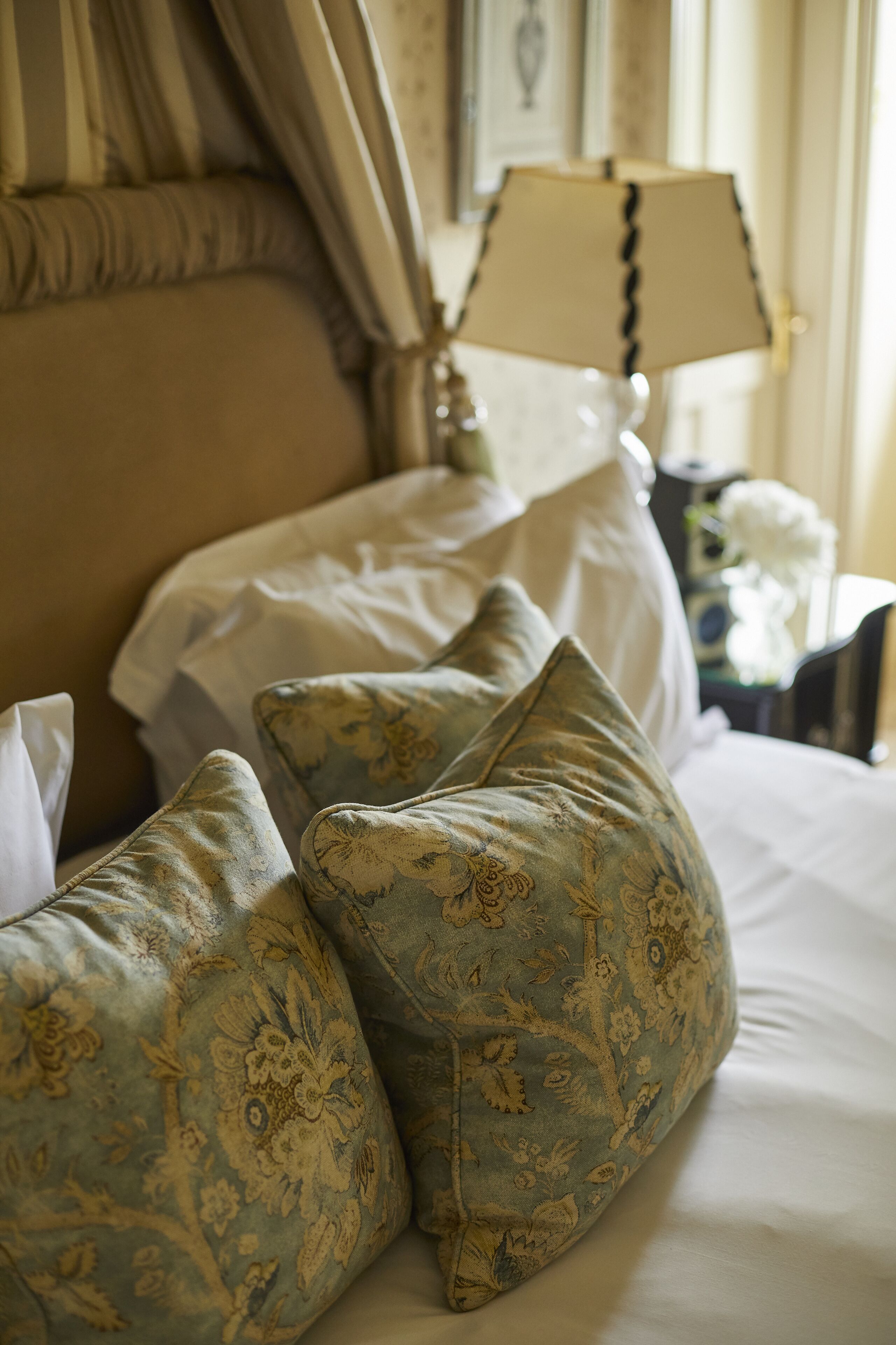 A bed with floral-patterned pillows and a white bedspread.