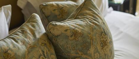 Un lit avec des oreillers à motifs floraux et un couvre-lit blanc.
