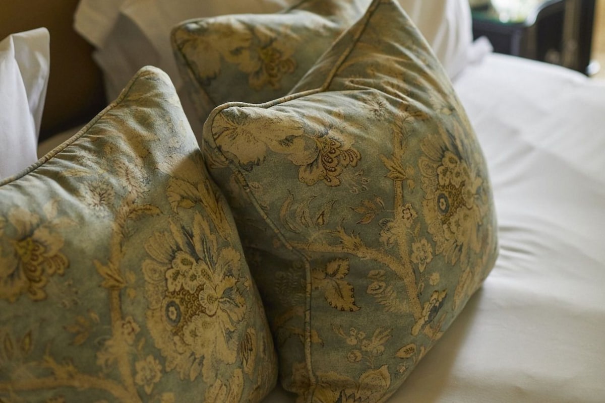 A bed with a canopy, a lamp, and decorative pillows.