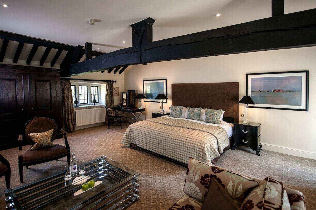 A bedroom with a large bed, a desk, a chair, and a view of the sea.