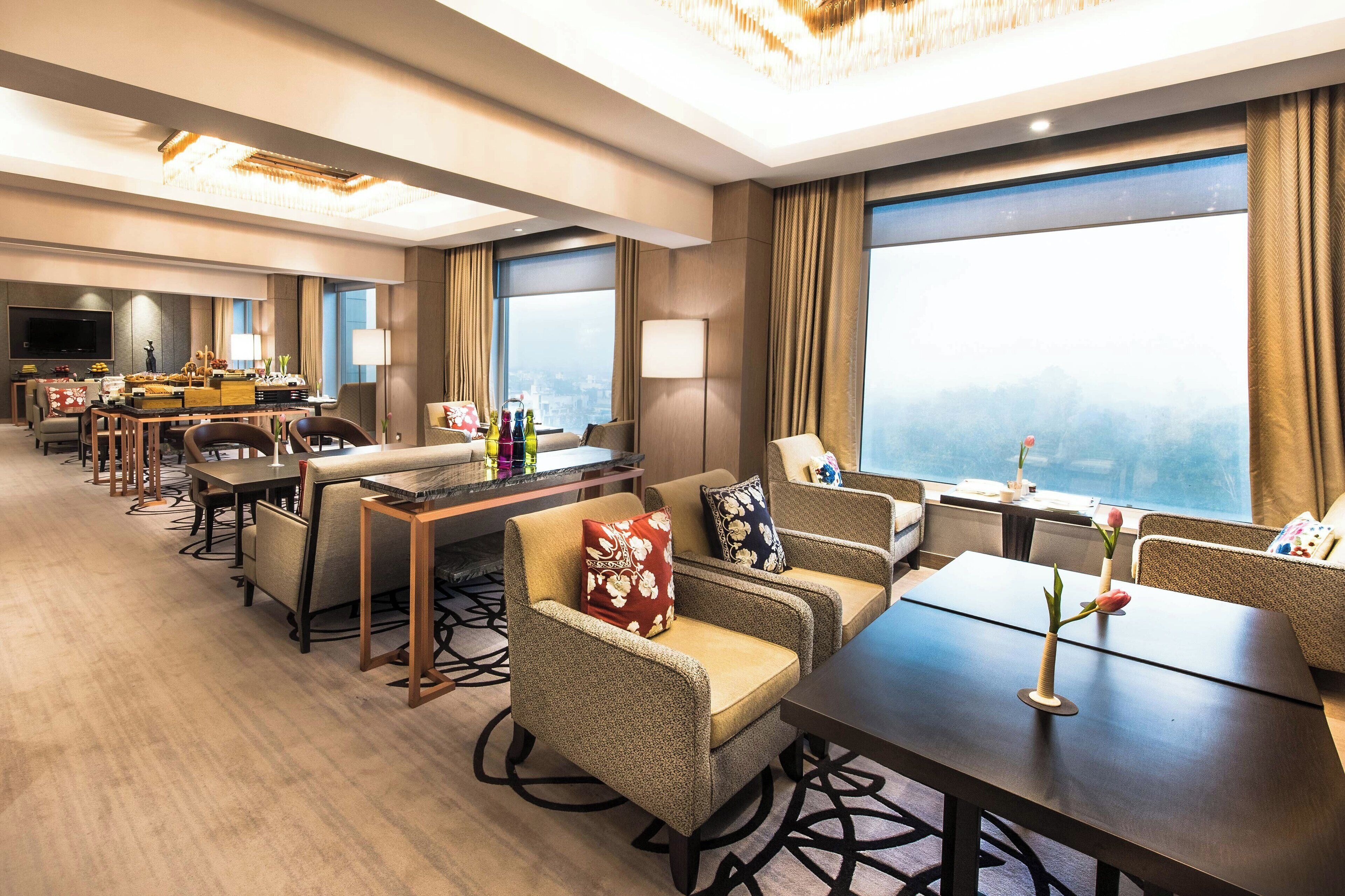 A hotel lobby with a dining area, seating arrangements, and large windows offering a city view.