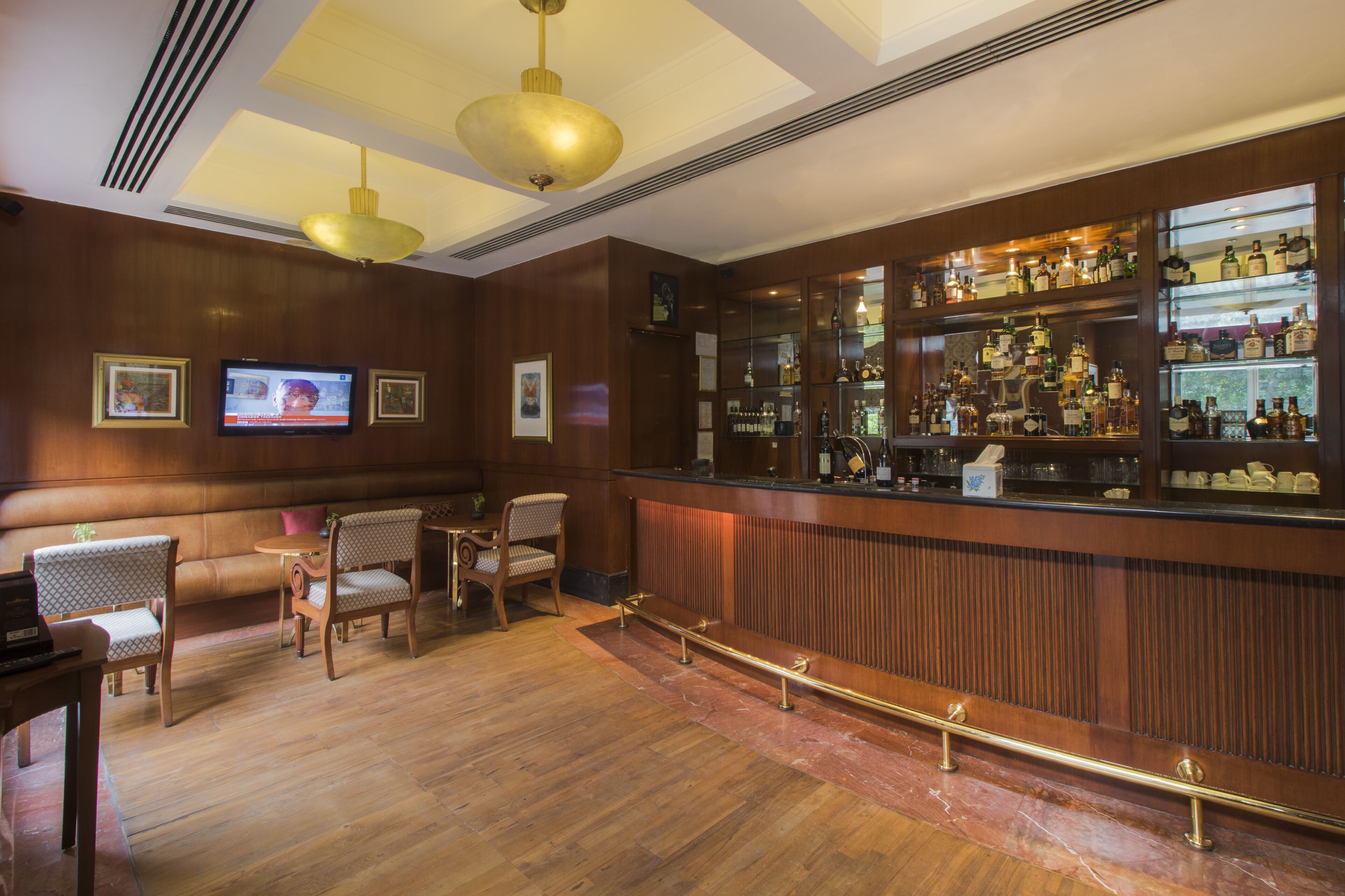 Zona de bar con paneles de madera, un televisor y una variedad de botellas de licores.