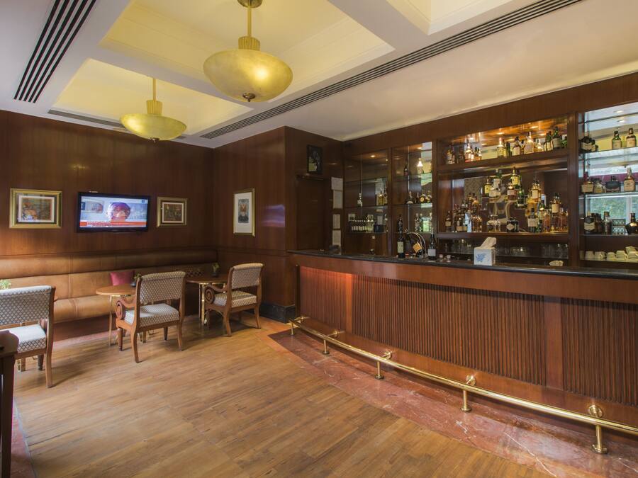 Zona de bar con paneles de madera, un televisor y una variedad de botellas de licores.