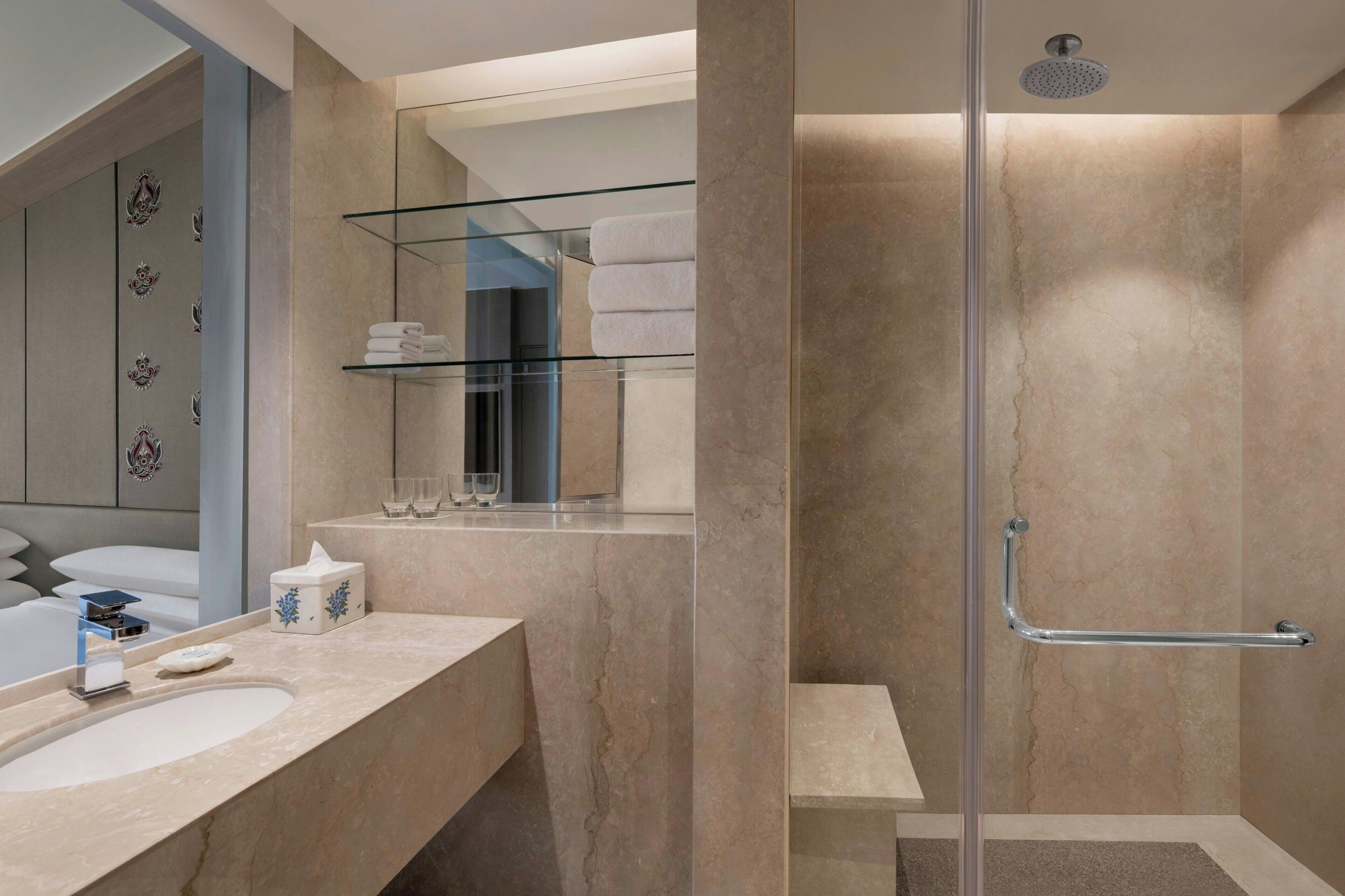 A modern bathroom with a glass shower enclosure, a vanity with a sink, and a towel rack.
