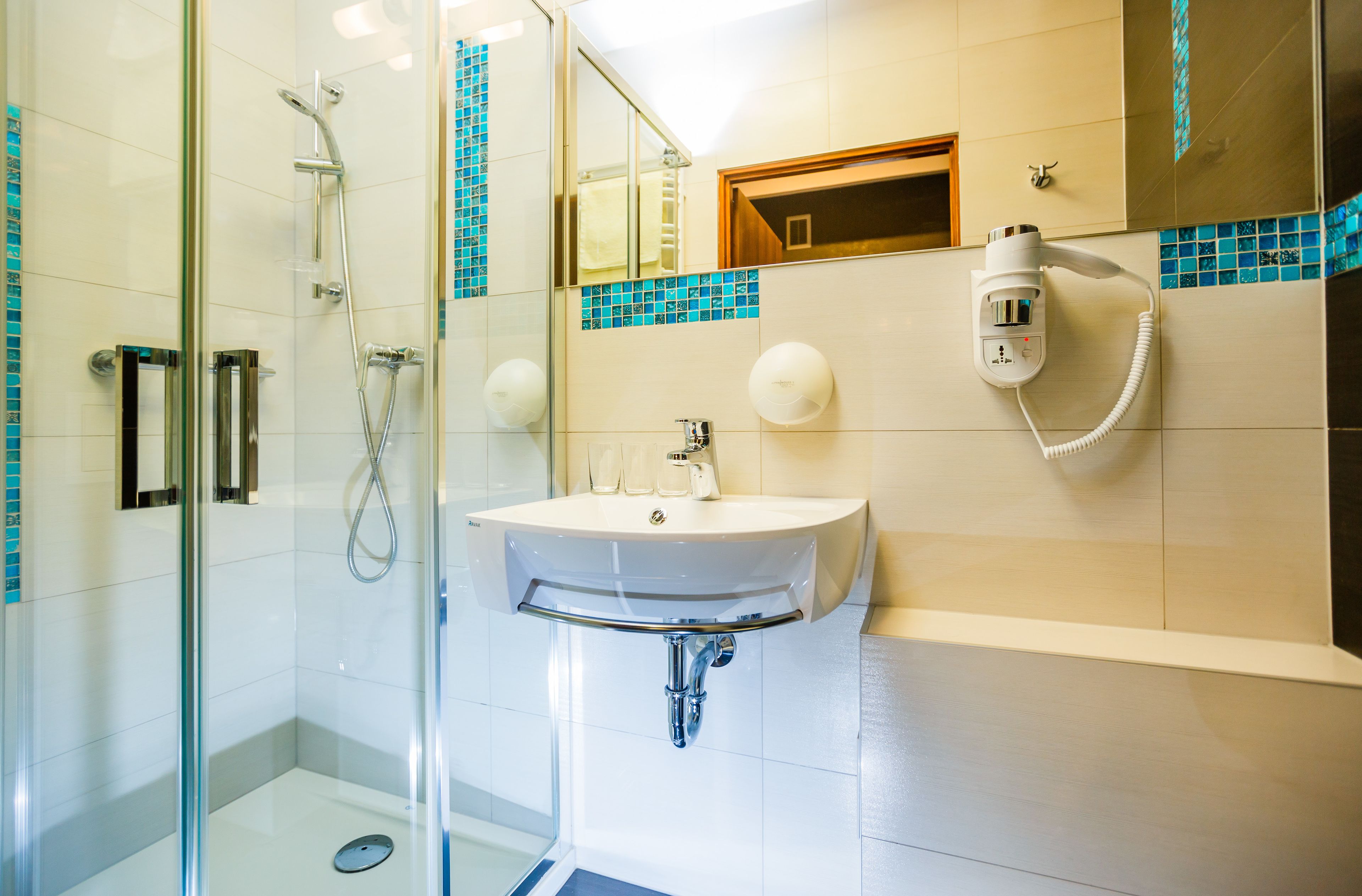 A bathroom with a glass shower enclosure, a sink with a mirror, and a towel rack.